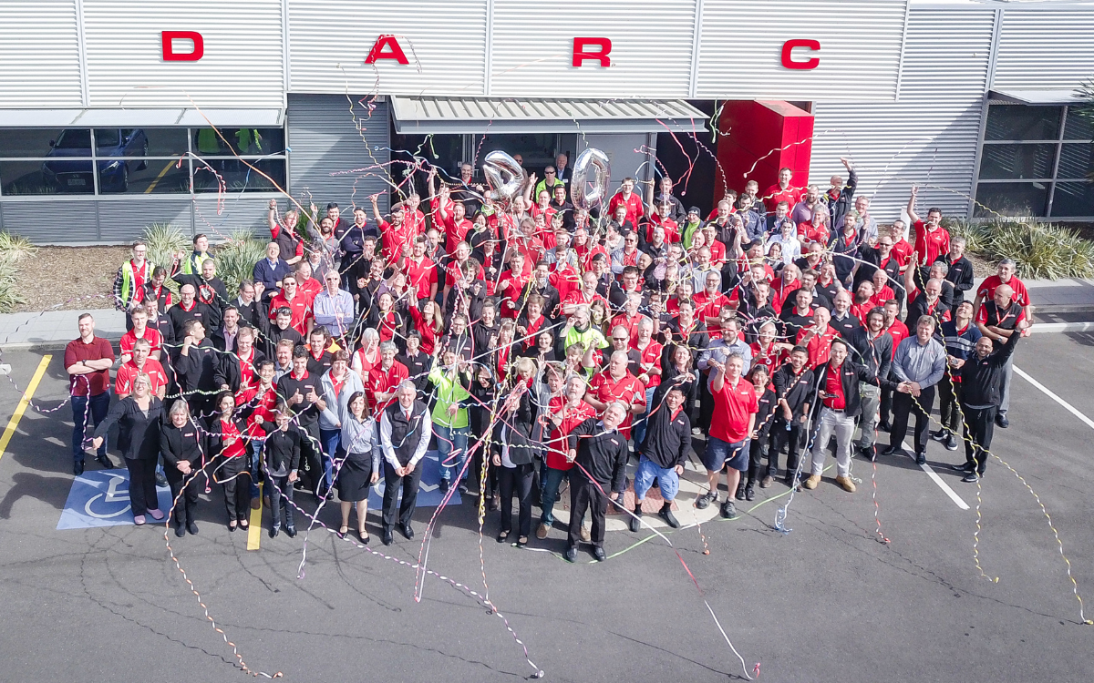 A large group of REDARC staff stand in front of the REDARC building the picture is taking from above and the staff are throwing streamers.