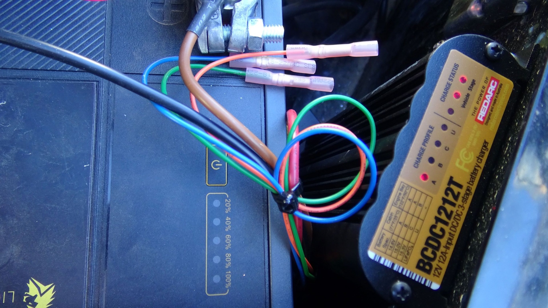 REDARC BCDC1212T trailer battery charger mounted next to a battery.